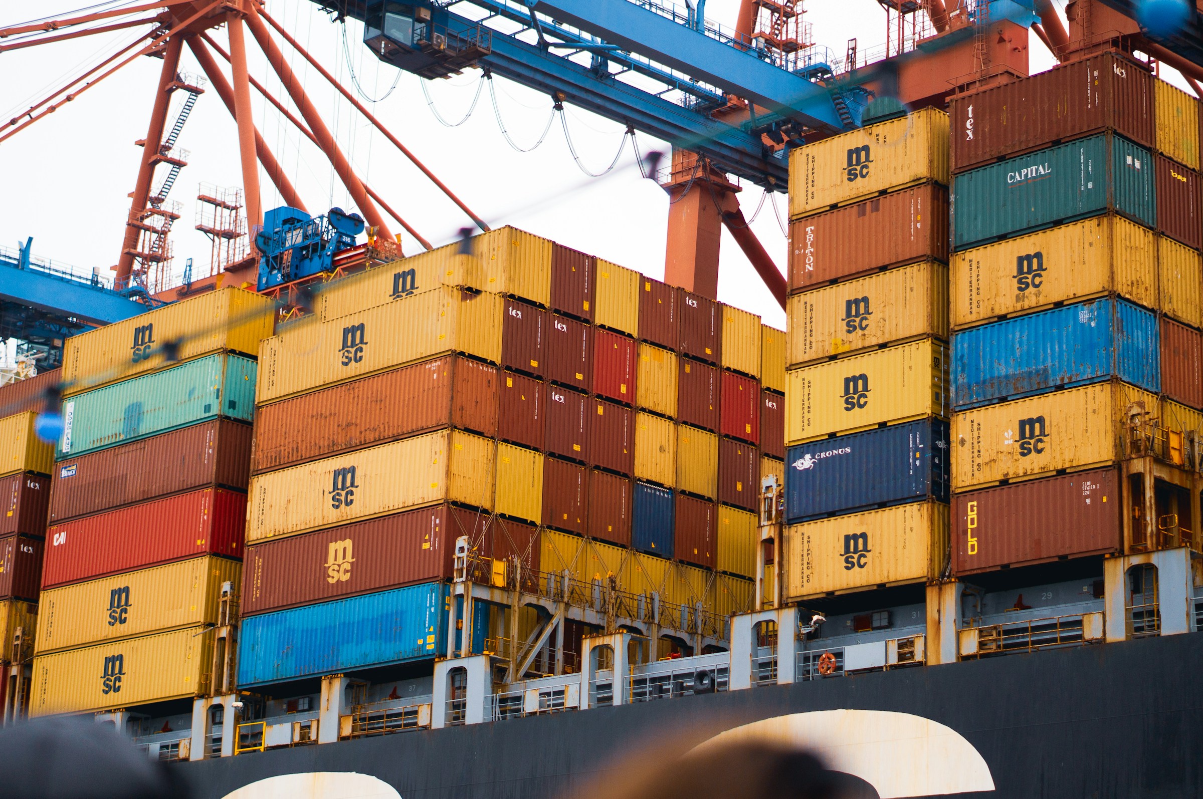 Stacks of shipping containers beneath terminal cranes.